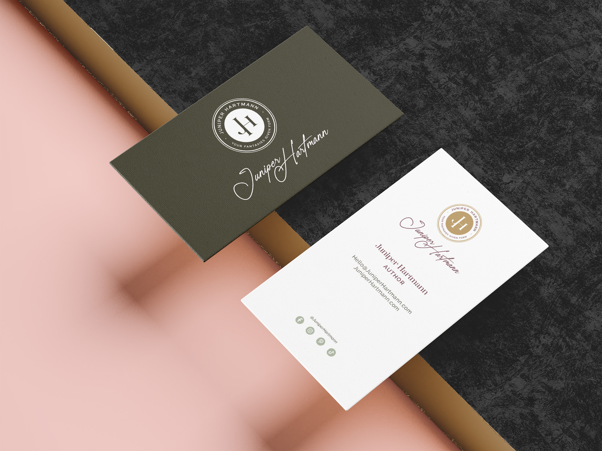 Two business cards for Juniper Hartmann, one in dark green and the other in white, displayed on a textured black and pink background. The logo is prominently featured on the card, with elegant typography and gold details.